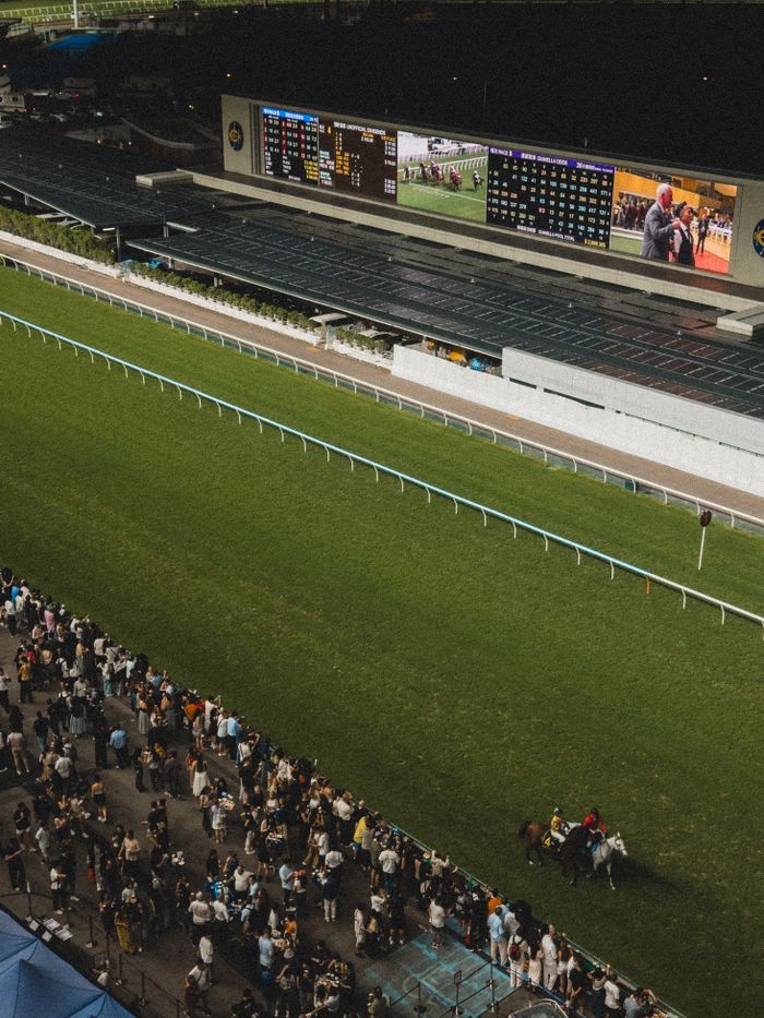 Aerial shot of a lively horse racing event at Happy Valley Racecourse in Hong Kong.